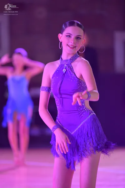 Dancesport competitor: Female dancer in foreground: purple Latin dance dress with a halter neck, rhines