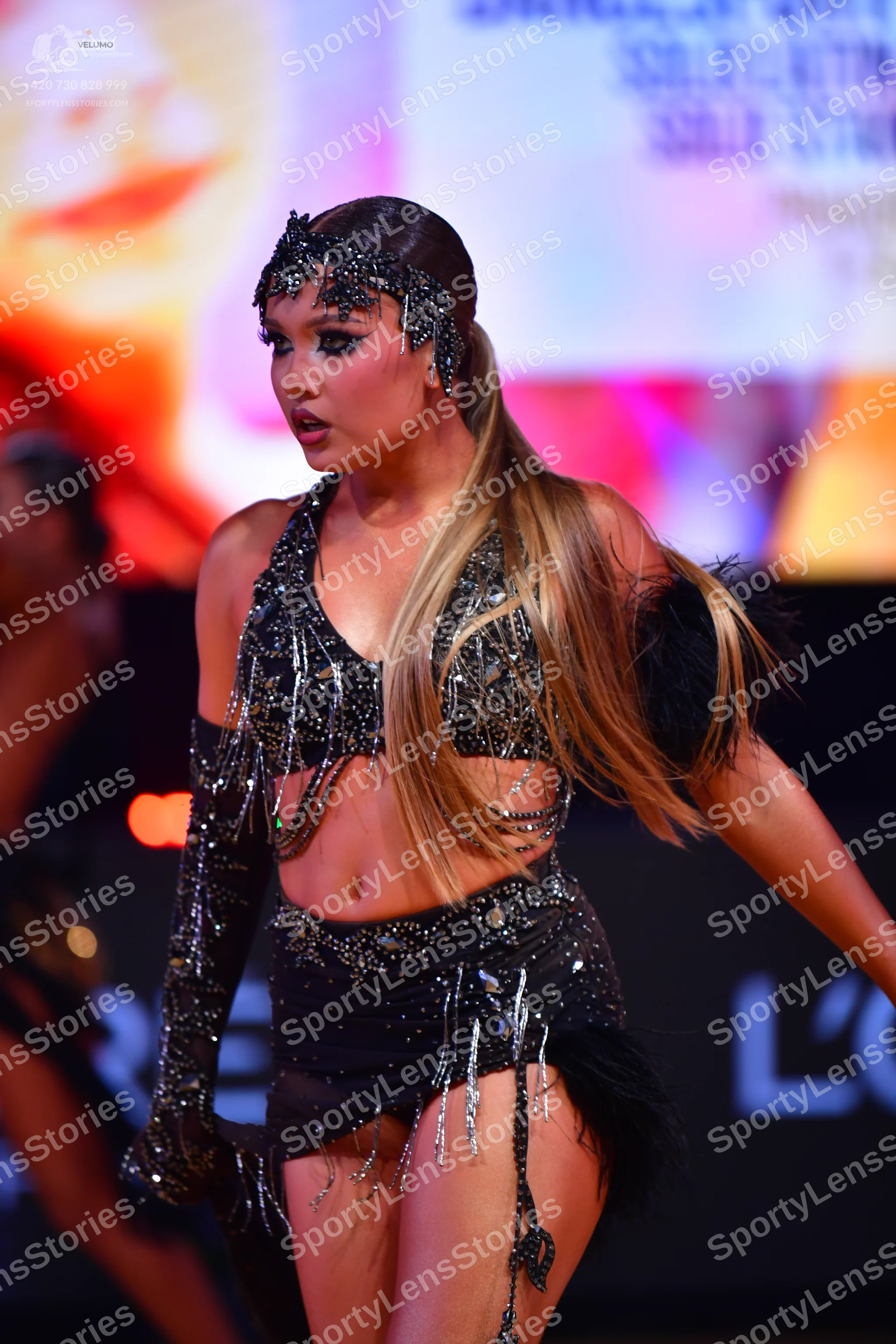 Dancesport competitor: Female dancer: black two-piece Latin costume heavily embellished with silver seq