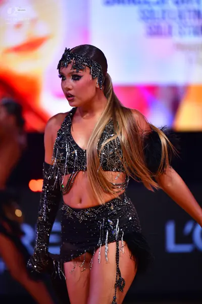 Dancesport competitor: Female dancer: black two-piece Latin costume heavily embellished with silver seq