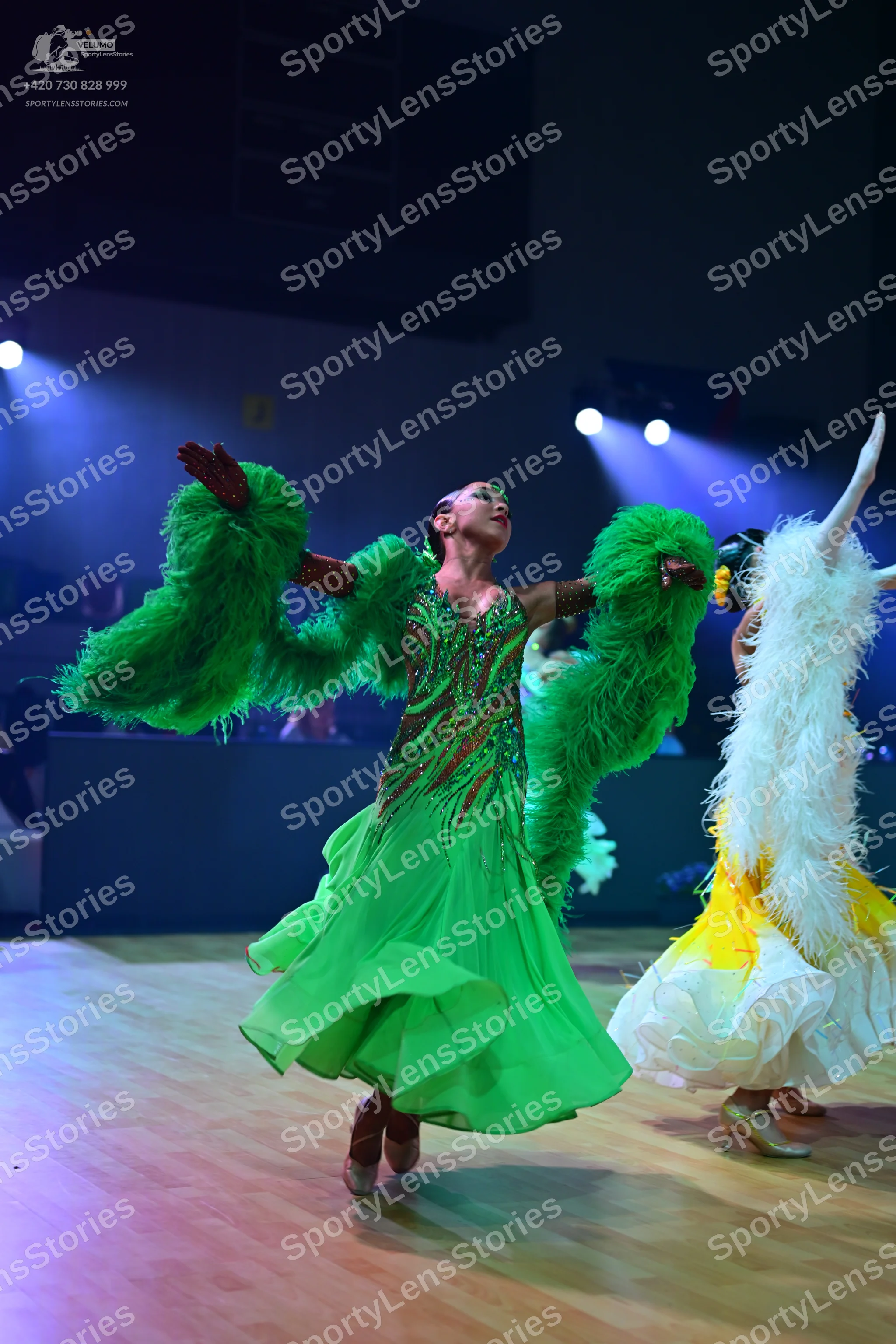 Dancesport competitor: Female dancer in center: bright green ballroom dress featuring a red and gold se