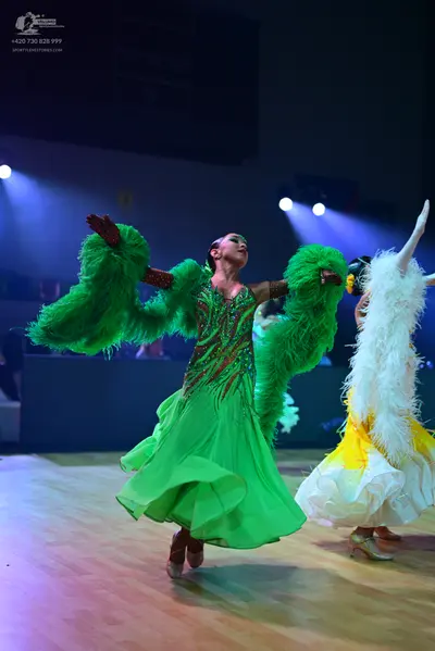 Dancesport competitor: Female dancer in center: bright green ballroom dress featuring a red and gold se