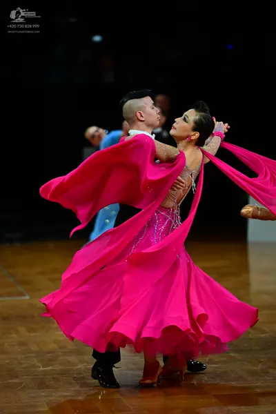 Dancesport competitor: Female dancer: bright pink ballroom gown with a sequined bodice and voluminous, 