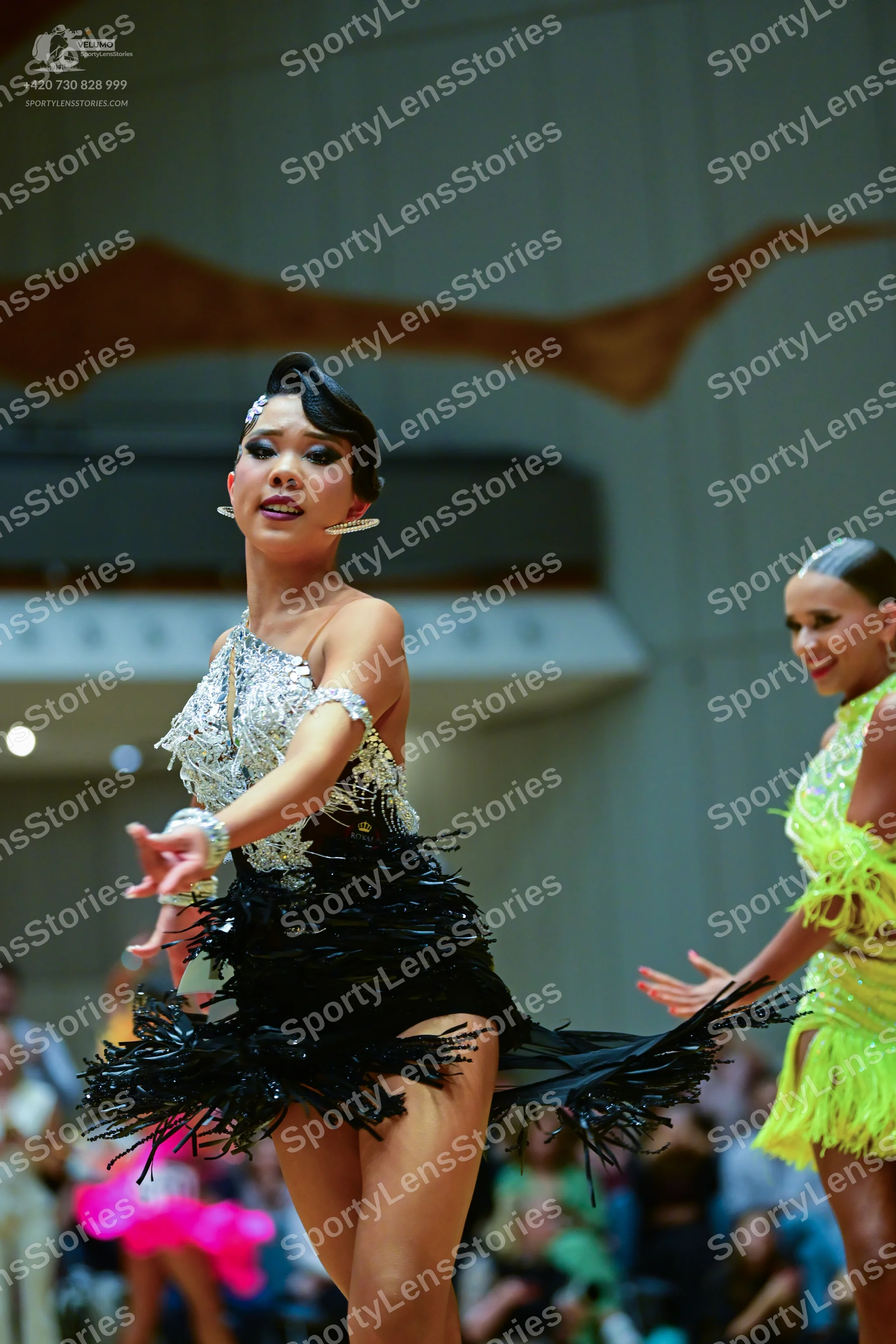 Dancesport competitor: Female dancer in foreground: silver and black Latin dress with a sequin bodice a