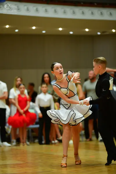 Dancesport competitor: Main female dancer: white latin dress with black trim and a ruffled, flared skir