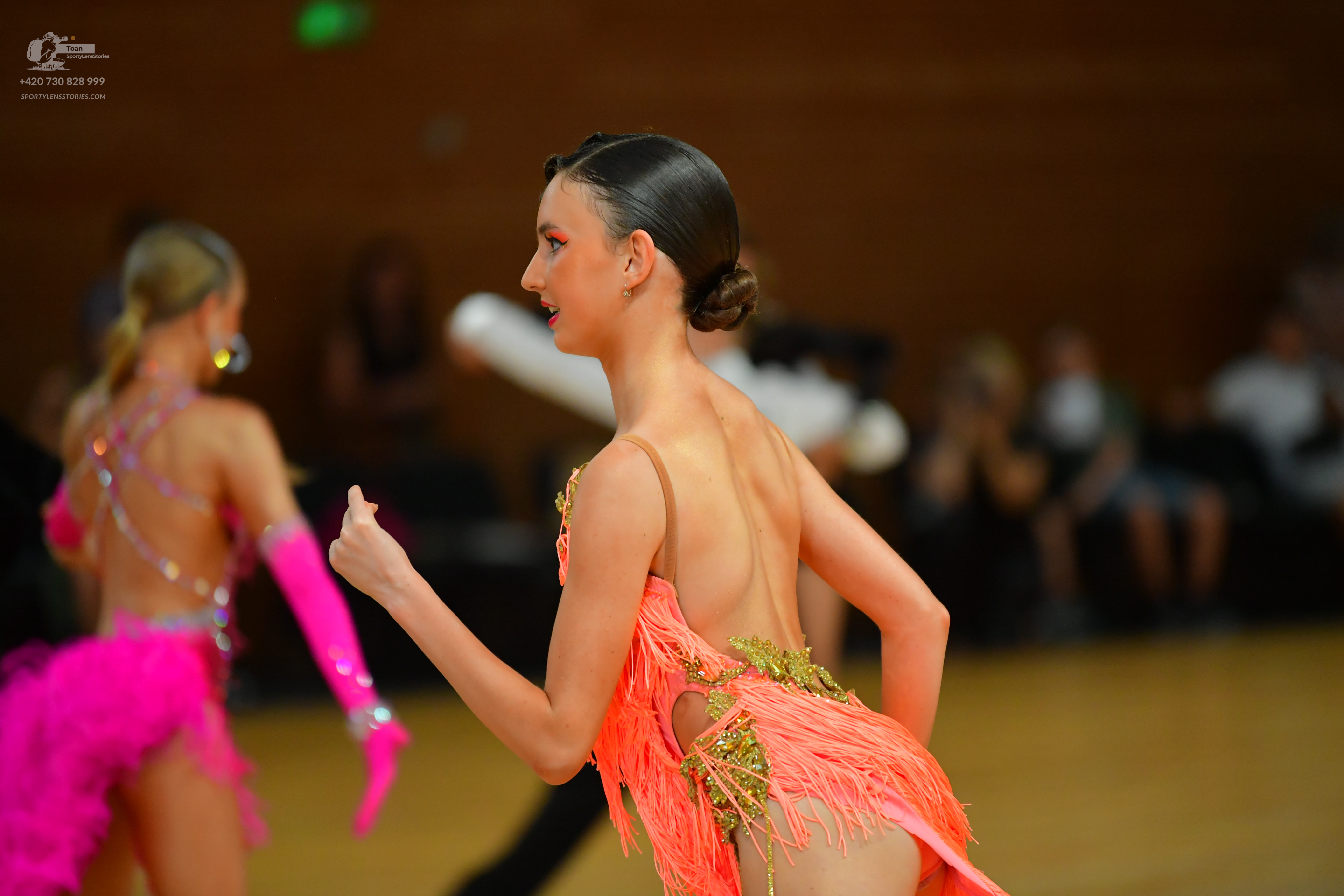 Dancesport competitor: ** Female: Orange latin dress with a plunging neckline, delicate fringe trim, an