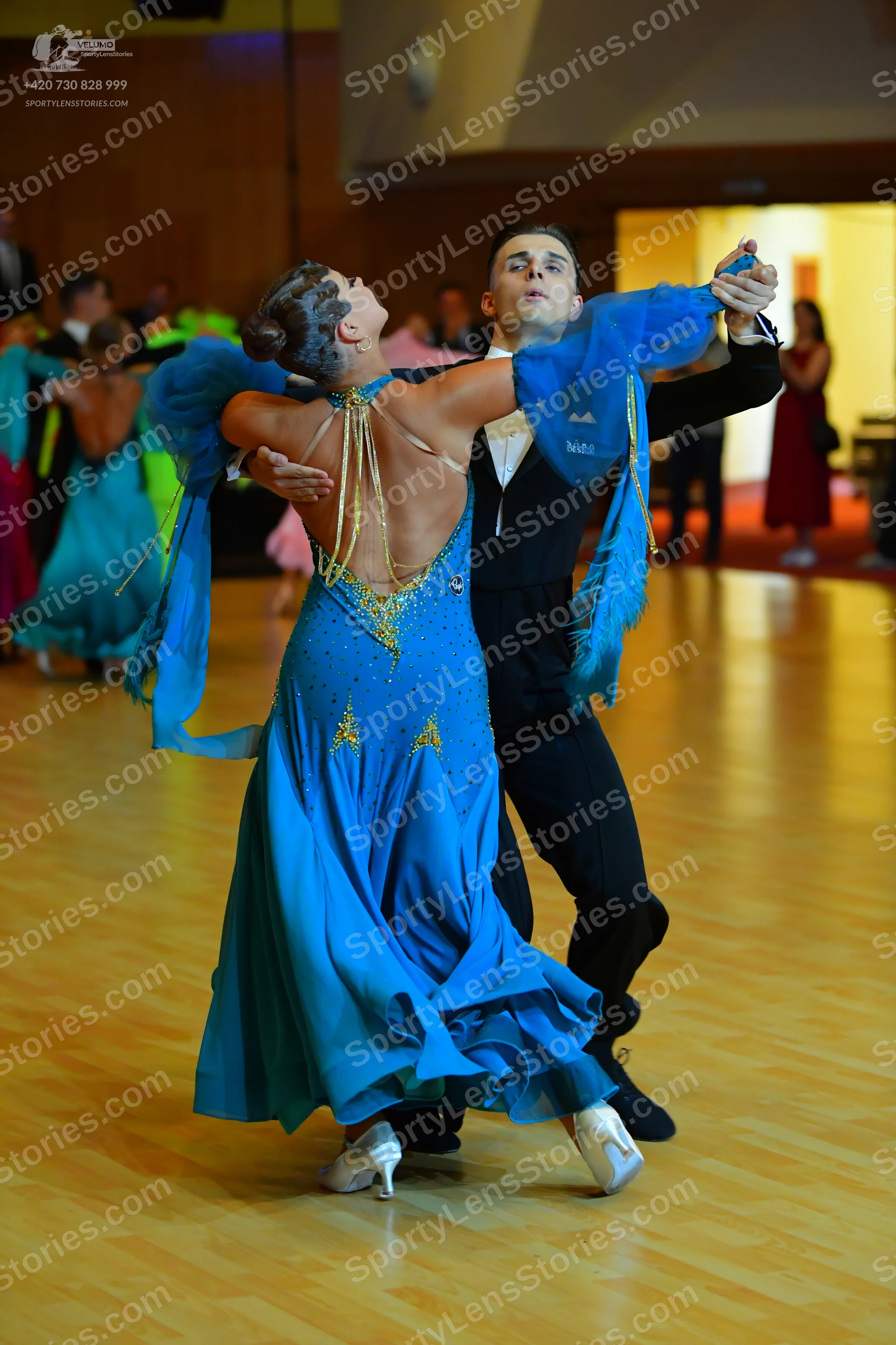 Dancesport competitor: Female dancer: bright blue satin ballroom gown with sparkly embellishments on th