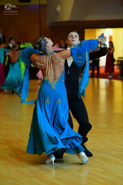 Dancesport competitor: Female dancer: bright blue satin ballroom gown with sparkly embellishments on th