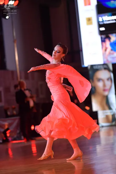 Dancesport competitor: Female dancer: pink long-sleeved latin dress with a ruffled skirt and matching l