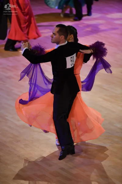Dancesport competitor: Okay, here's a description of the dancers' costumes in the photo, broken down as