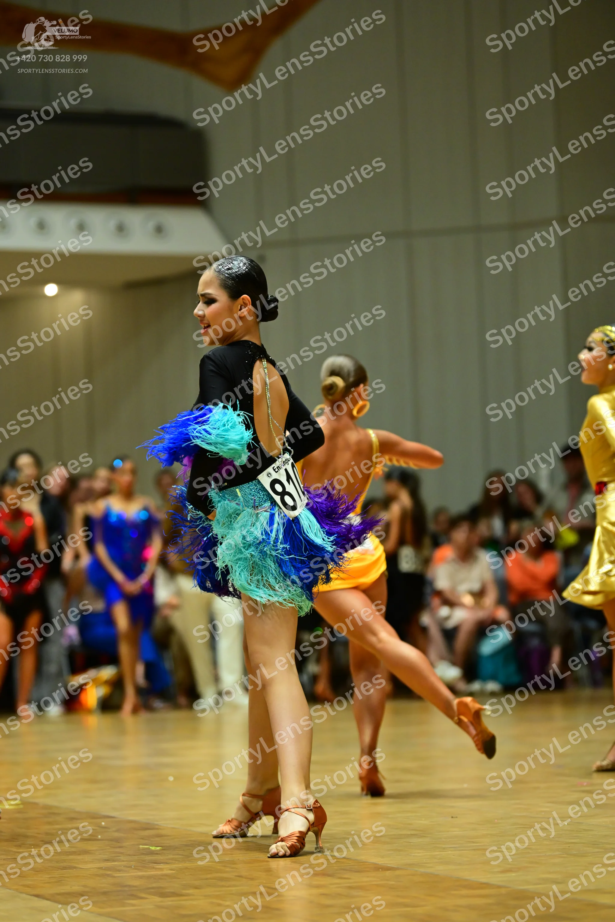 Dancesport competitor #81: Female dancer 1: black long-sleeve latin dress with an open back and multi-color