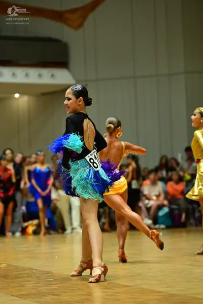 Dancesport competitor #81: Female dancer 1: black long-sleeve latin dress with an open back and multi-color