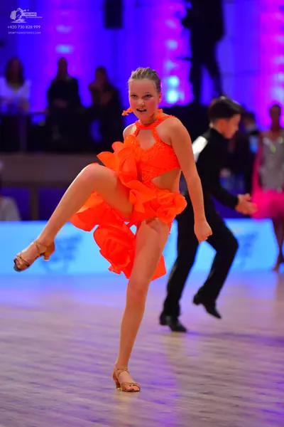 Dancesport competitor: Female dancer: bright orange latin dress with a halter neck and ruffled skirt