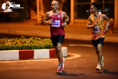 Marathon runner #42098, #42190: Runner 1: maroon tank top, black shorts, grey and pink running shoes, dark watch
