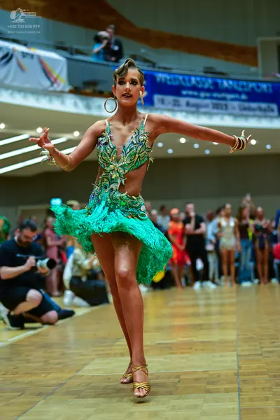 Dancesport competitor: Female dancer: green Latin dance dress with a fringed skirt and a patterned bodi