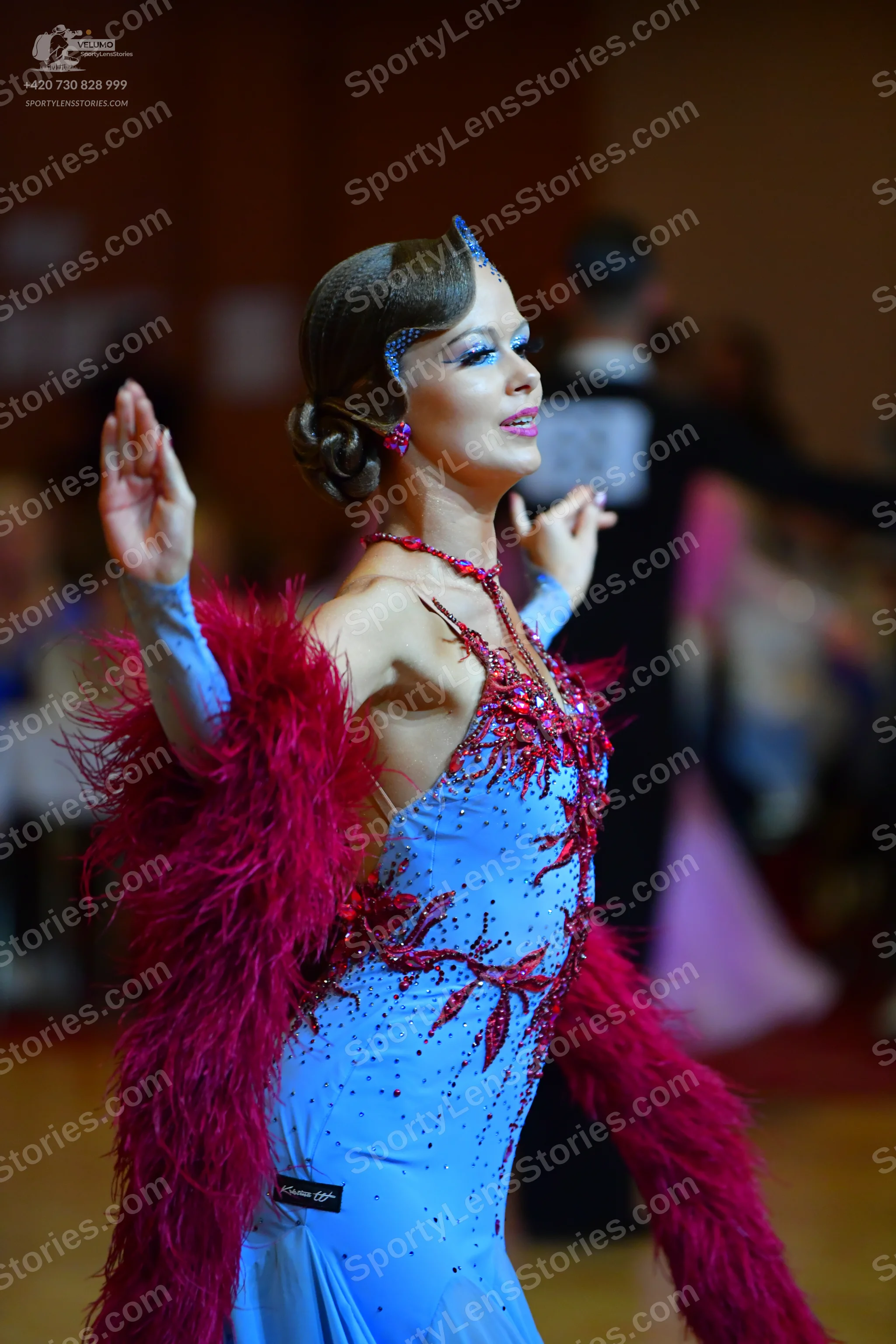 Dancesport competitor: Female dancer: light blue Latin dance dress with red sequin embellishments and a