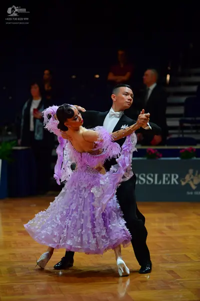 Dancesport competitor: Female dancer: voluminous light purple ballroom dress with many ruffles and laye