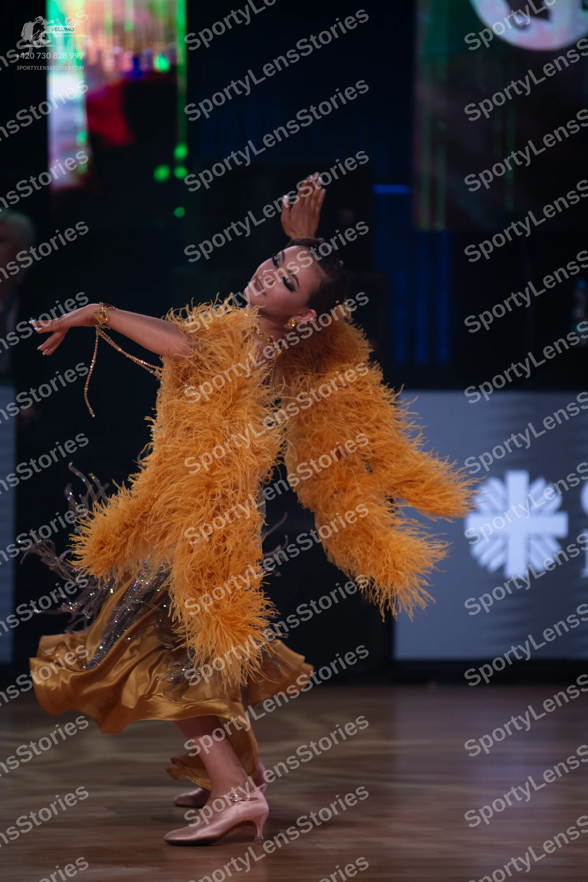 Dancesport competitor: Female dancer: gold/mustard Latin dance dress featuring large, voluminous yellow