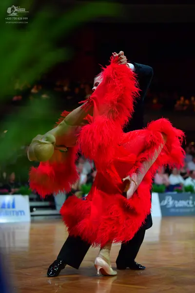 Dancesport competitor: Female dancer: red Latin dress with large red feathers