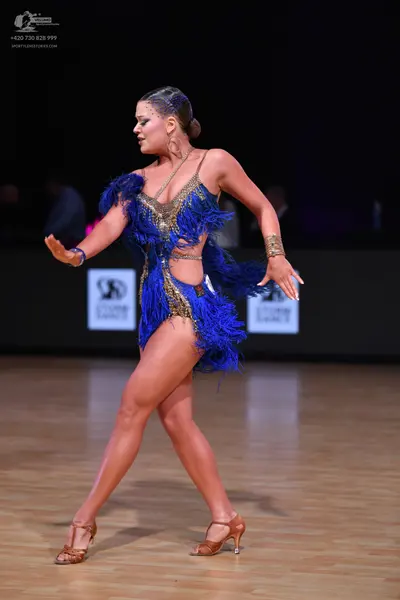 Dancesport competitor: Female dancer: blue Latin dress with blue feathers and gold-toned embellishments