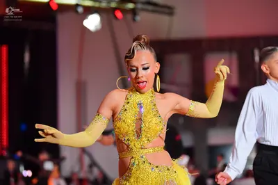 Dancesport competitor: Female dancer: yellow latin dress with sequins and cut-outs, matching long yello