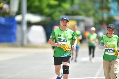 Marathon runner #5274, #5257: Runner 1: green jersey, black shorts, blue cap, black knee brace