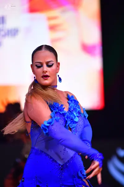 Dancesport competitor: Female dancer: blue Latin dress with blue 3D floral embellishments, blue sequins