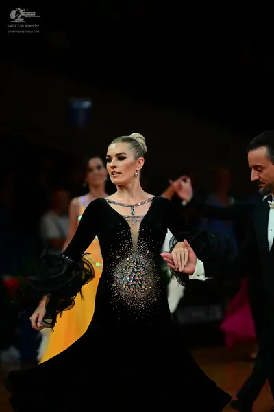 Dancesport competitor: Main female dancer: black long-sleeved ballgown with a deep V-neckline, crystal 