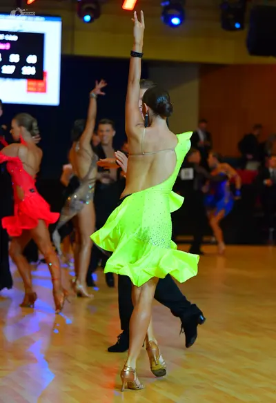 Dancesport competitor: Female dancer in foreground: lime green latin dress with small sparkly rhineston
