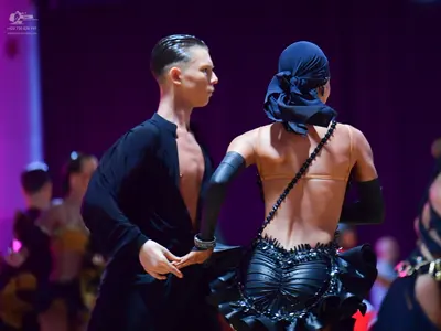 Dancesport competitor: Male dancer: black long-sleeved Latin-style shirt, unbuttoned at the chest