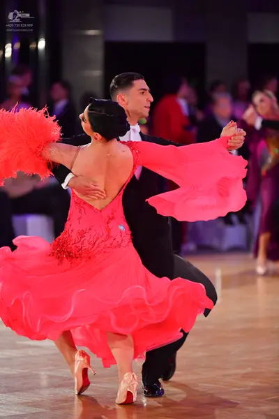 Dancesport competitor: Female dancer: bright coral ballroom dress with a voluminous ruffled skirt and l