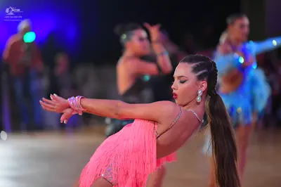 Dancesport competitor: Female dancer in foreground: pink latin dress with long fringe