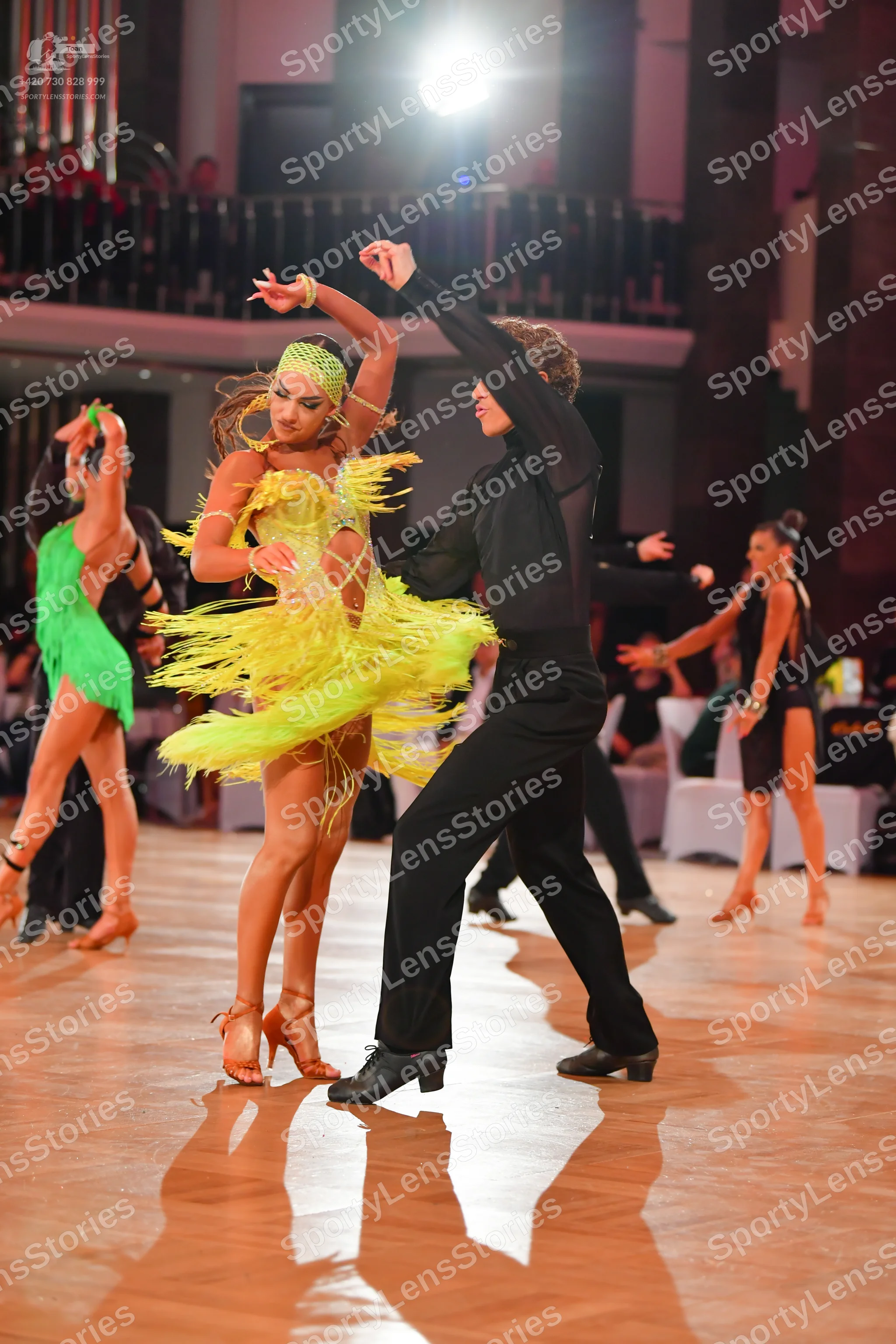Dancesport competitor: Female dancer in foreground: lime green Latin dress with long fringe