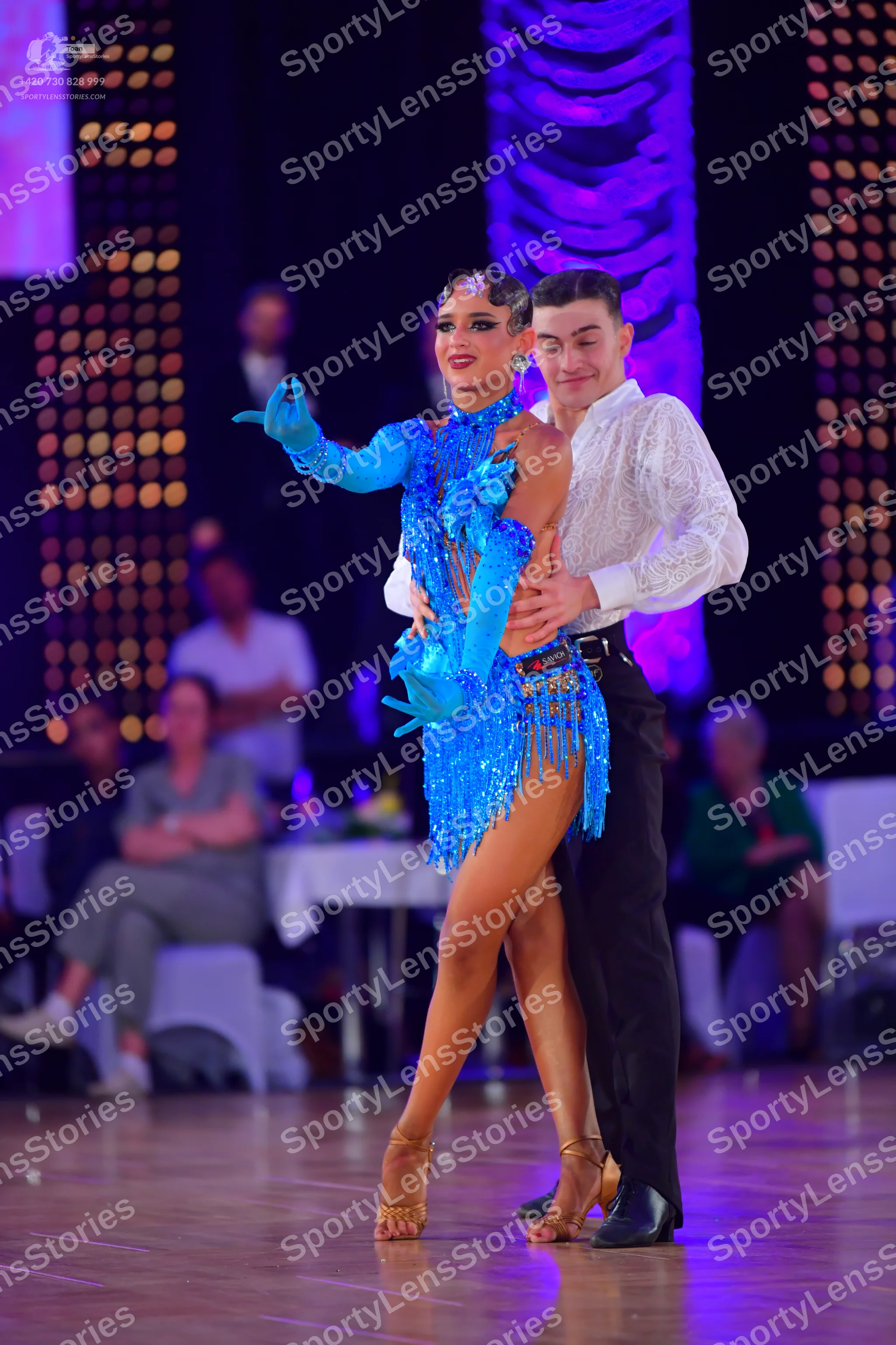 Dancesport competitor: Female dancer: bright blue latin dance dress with sequins and fringe, including 