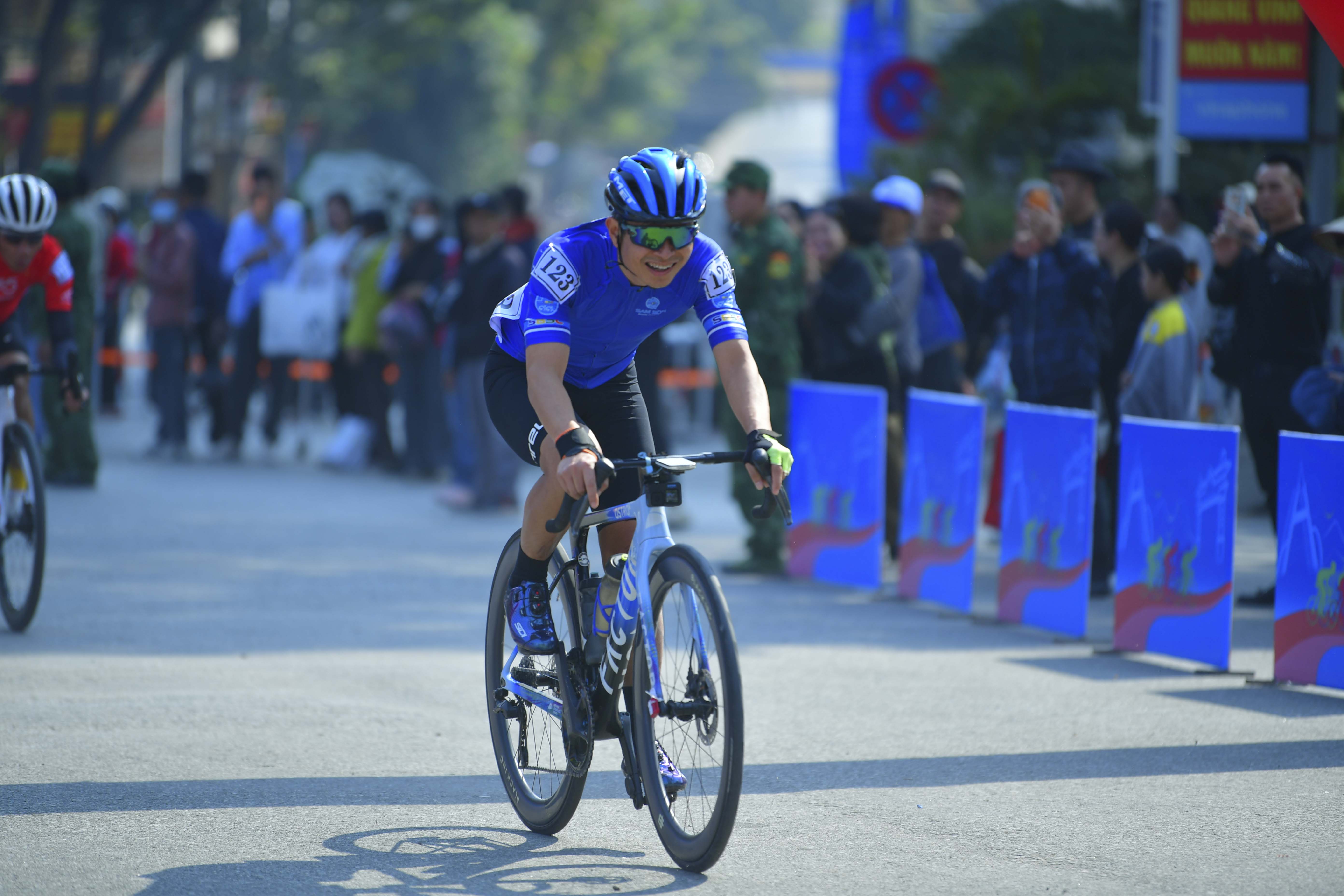Cyclist: Cyclist 1: Blue and white jersey, black shorts, blue helmet