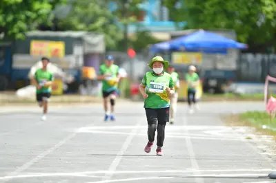 Marathon runner #5320: Runner 1: green jersey, black leggings, pink shoes, green sun hat, white face ma