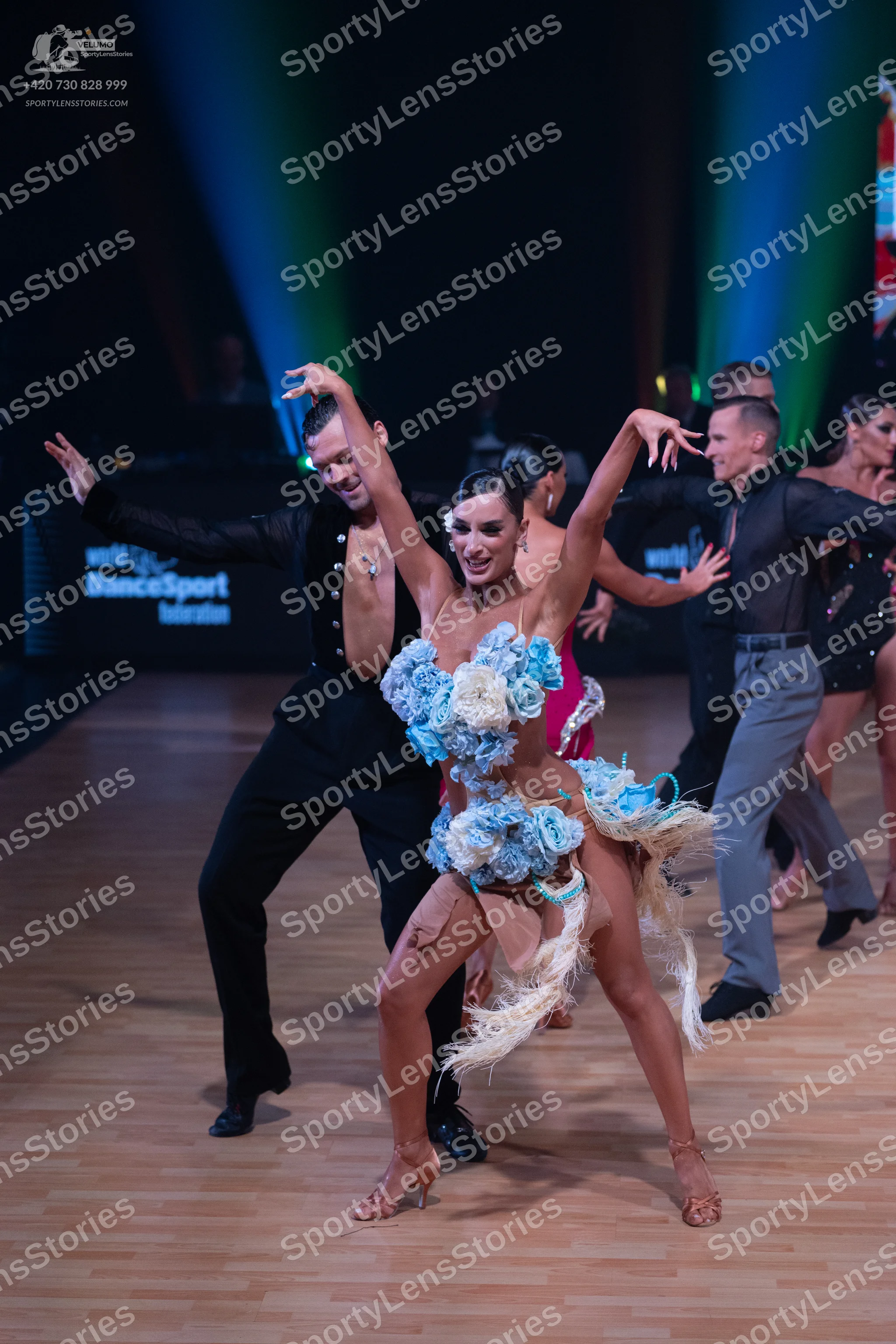 Dancesport competitor: Female dancer: light blue and white Latin dress with large 3D floral embellishme