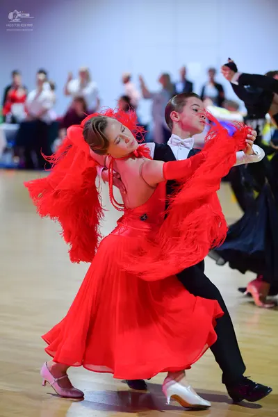Dancesport competitor: Female dancer: red Latin dress with long red fringe on the sleeves and back, pai