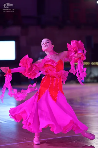 Dancesport competitor: Female dancer: vibrant pink ballgown with a decorated bodice, voluminous ruffled