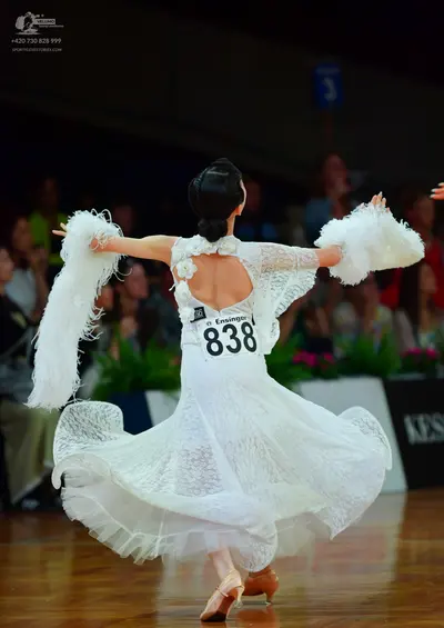 Dancesport competitor: Female dancer: white lace ballroom dress with a voluminous, flowing skirt