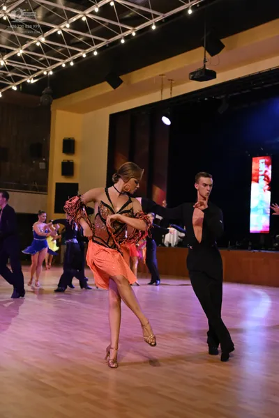 Dancesport competitor: Female dancer: coral-colored Latin dress with a dark, heavily sequined and embel