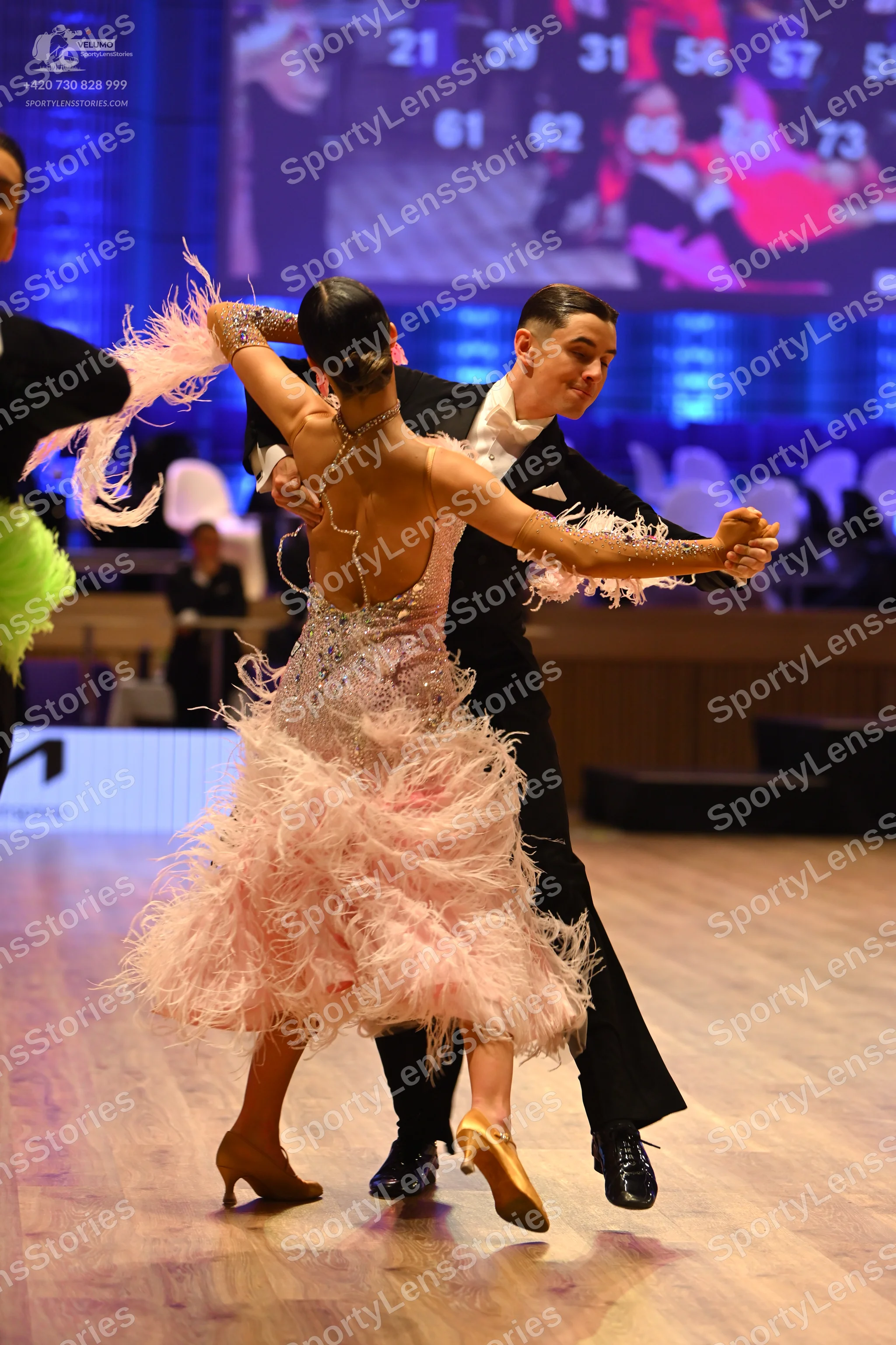 Dancesport competitor: Female dancer: light pink Latin dress with extensive feather trim and a backless