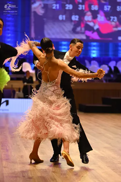 Dancesport competitor: Female dancer: light pink Latin dress with extensive feather trim and a backless