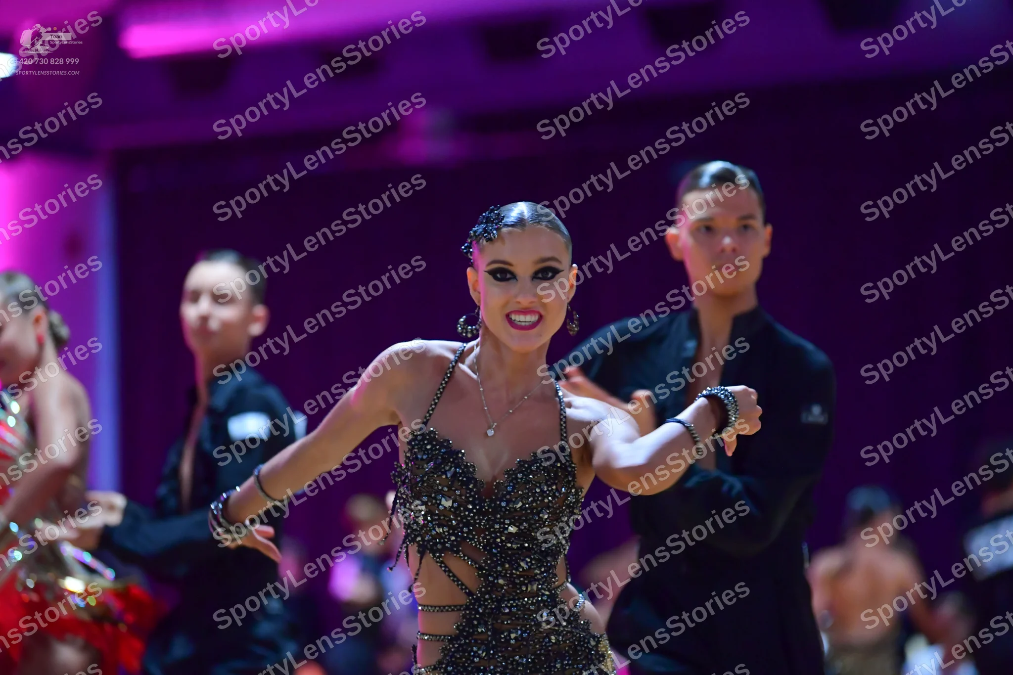 Dancesport competitor: Central female dancer: black sequined latin dress with thin straps and heavy emb