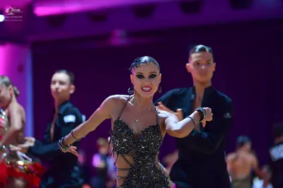 Dancesport competitor: Central female dancer: black sequined latin dress with thin straps and heavy emb