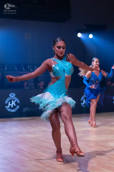 Dancesport competitor: Female dancer in foreground: turquoise latin dress with sequins and feather/frin