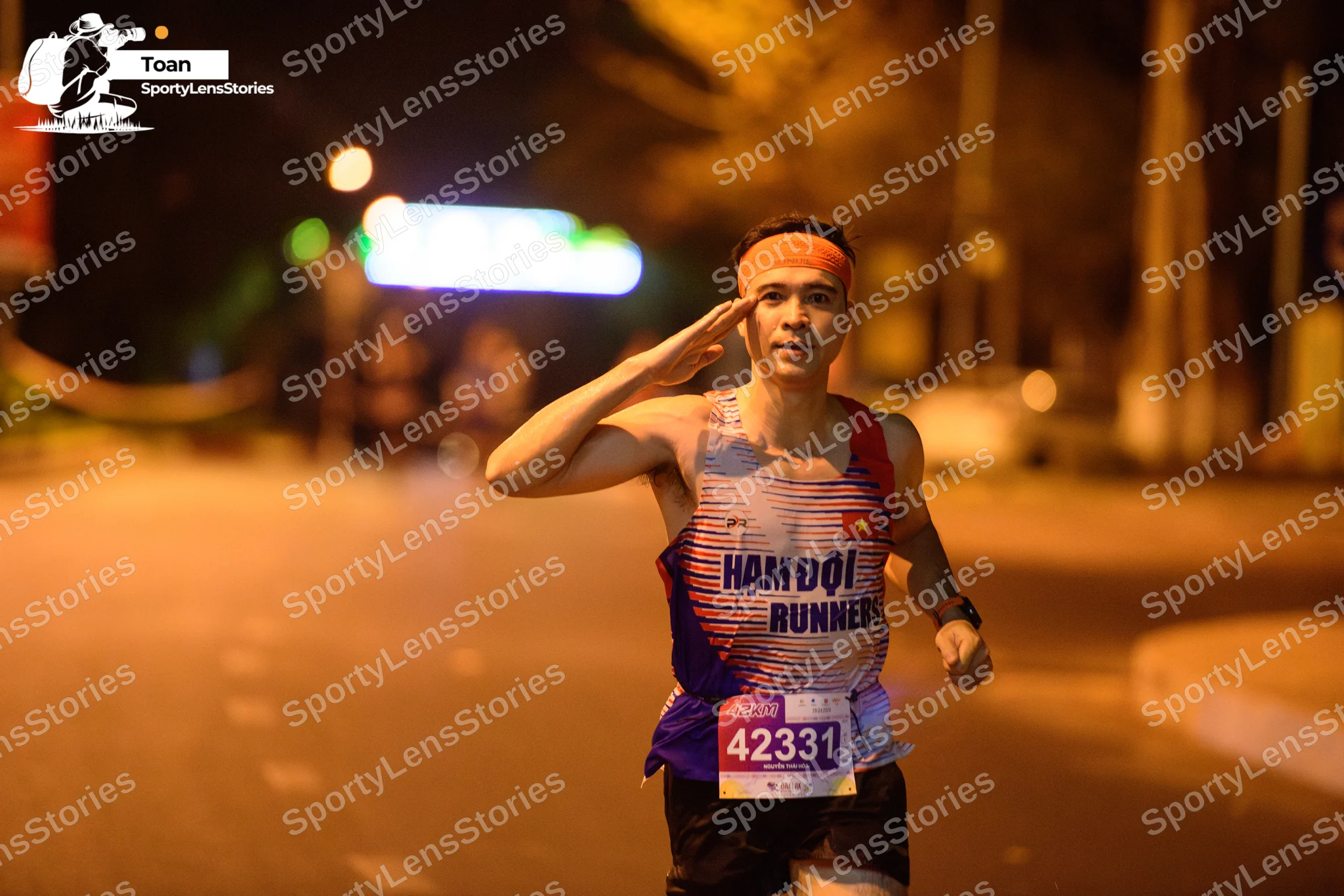Marathon runner #42331: Runner 1: blue, red, and white patterned tank top, black shorts, orange headband