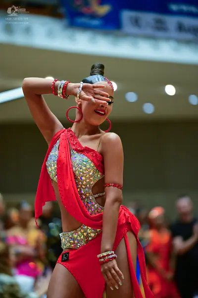 Dancesport competitor: Female dancer: red Latin dress with sequins, featuring an asymmetrical one-shoul