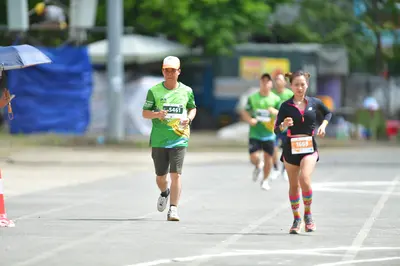 Marathon runner #M5461, #1069: Runner 1: green jersey, grey shorts, white socks, white shoes, white cap
