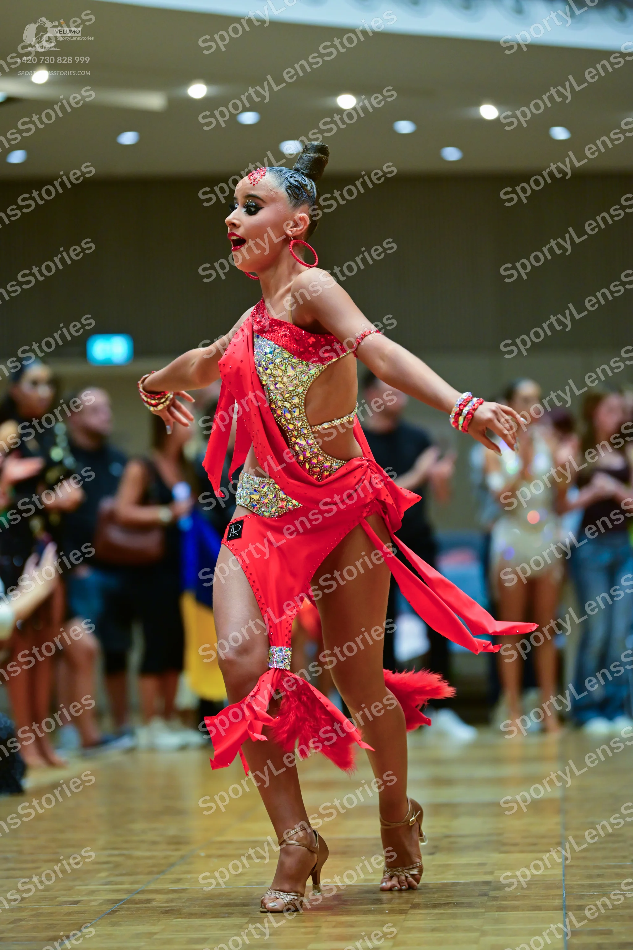 Dancesport competitor: Female dancer: red latin dress with gold and silver sequins, featuring an asymme