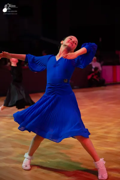 Dancesport competitor: Main dancer: royal blue dress with long puffed pleated sleeves and a flowing ple